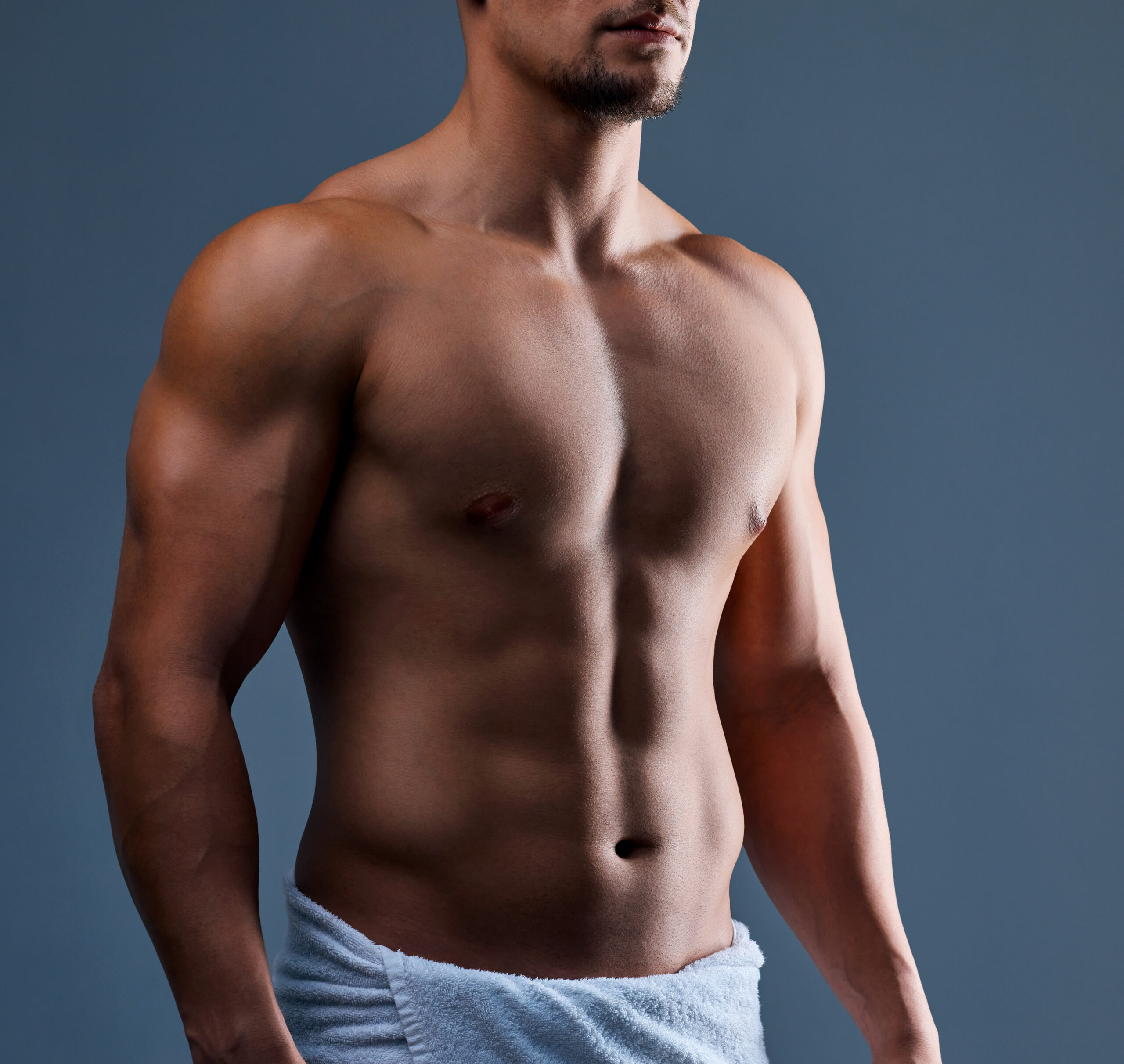 Cropped shot of an unrecognizable man posing in a towel against a grey background.